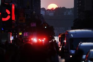 crowds gather to watch "manhattanhenge," when the sunset aligns with manhattan's street grid