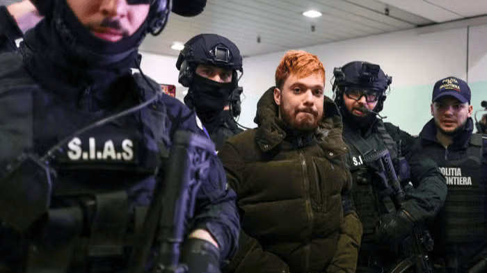 mohamed amra, escorté par des policiers roumains, à l’aéroport de bucarest, le 23 février 2025, avant d’être renvoyé en france. octav ganea afp